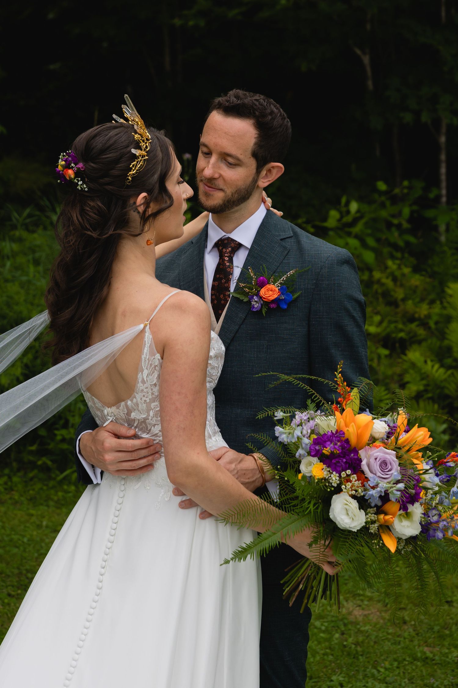 Romantic wedding portrait with colorful bouquet and mountain scenery.