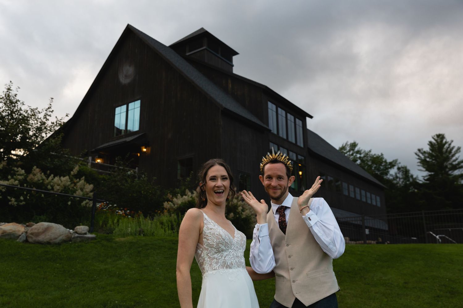 A couple poses in front of a rustic barn venue during their wedding celebration.