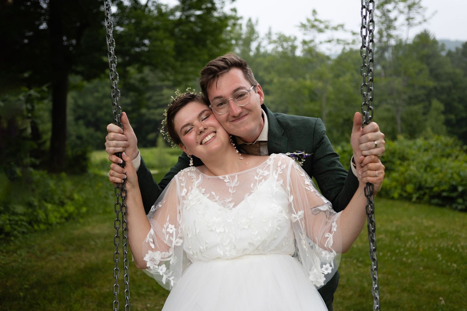 A romantic moment captured on a swing set at an outdoor wedding venue.