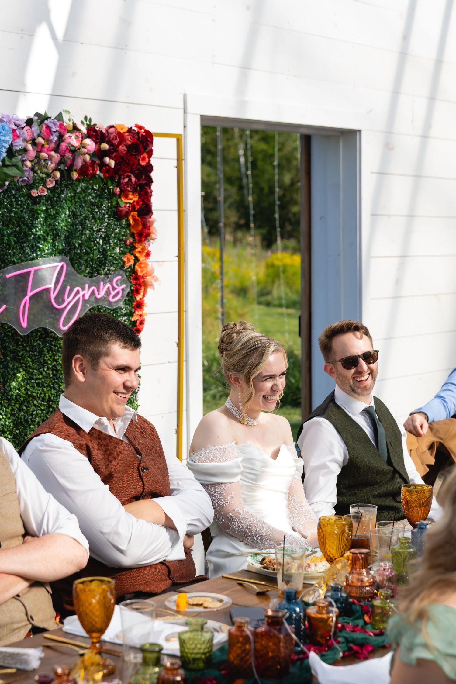 Reception guests enjoying drinks and conversation at decorated tables with amber glassware and floral arrangements.