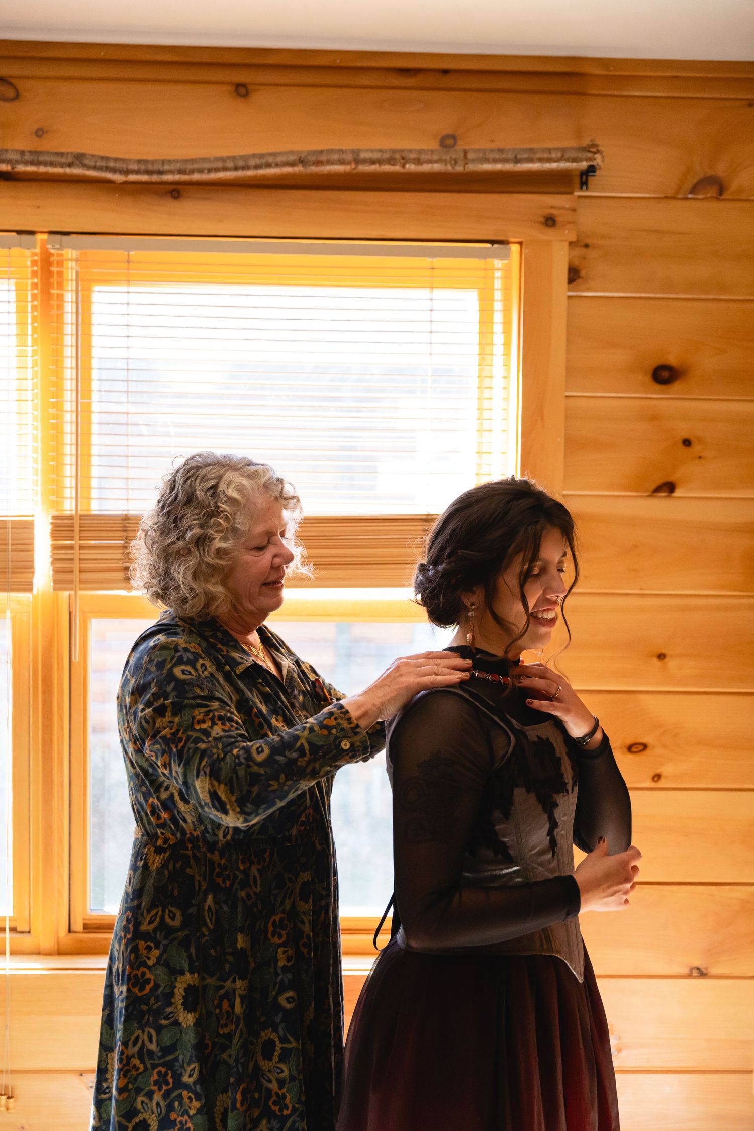 Two people share a candid moment in a wood-paneled room with natural light streaming through windows.