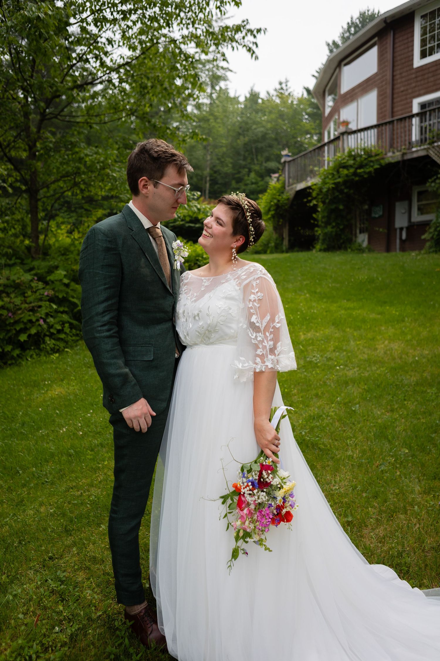 Garden wedding portrait with couple sharing a moment while holding colorful bouquet.