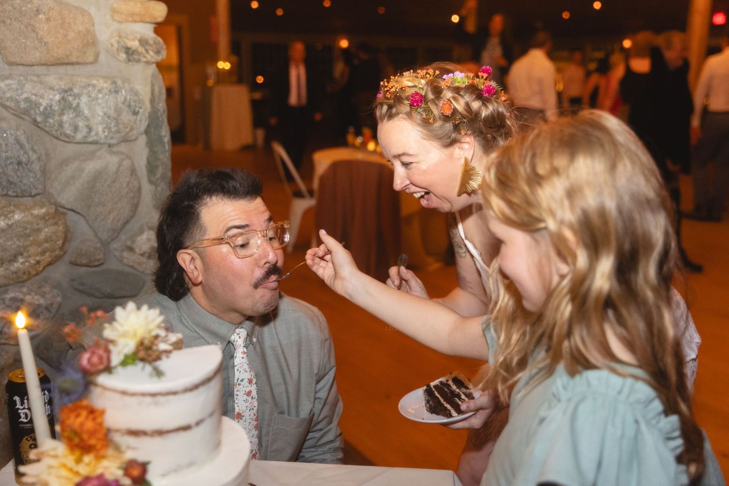 A joyful cake-feeding moment between family members at a wedding reception.