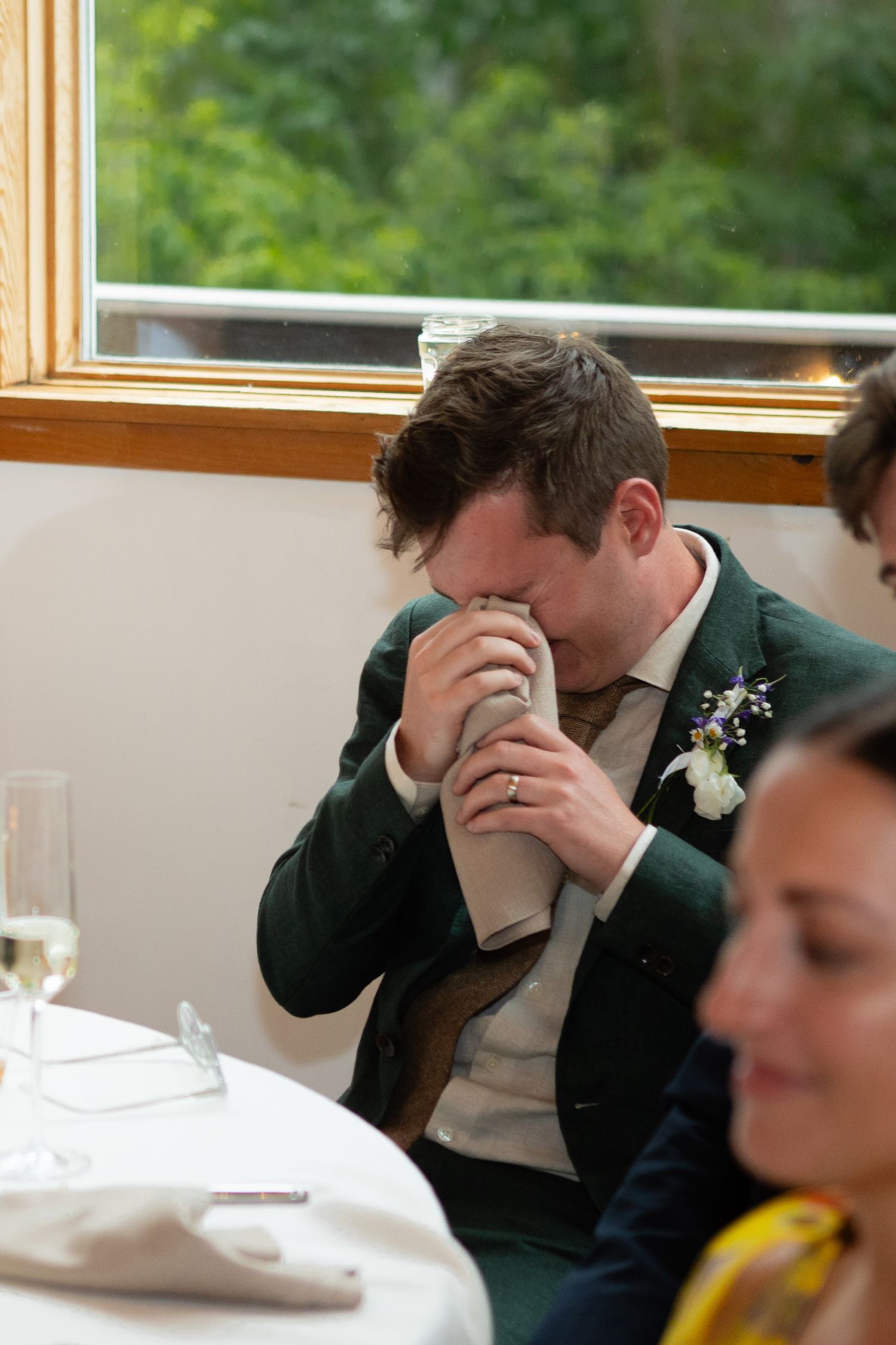 Wedding guest having an emotional moment at reception dinner table.