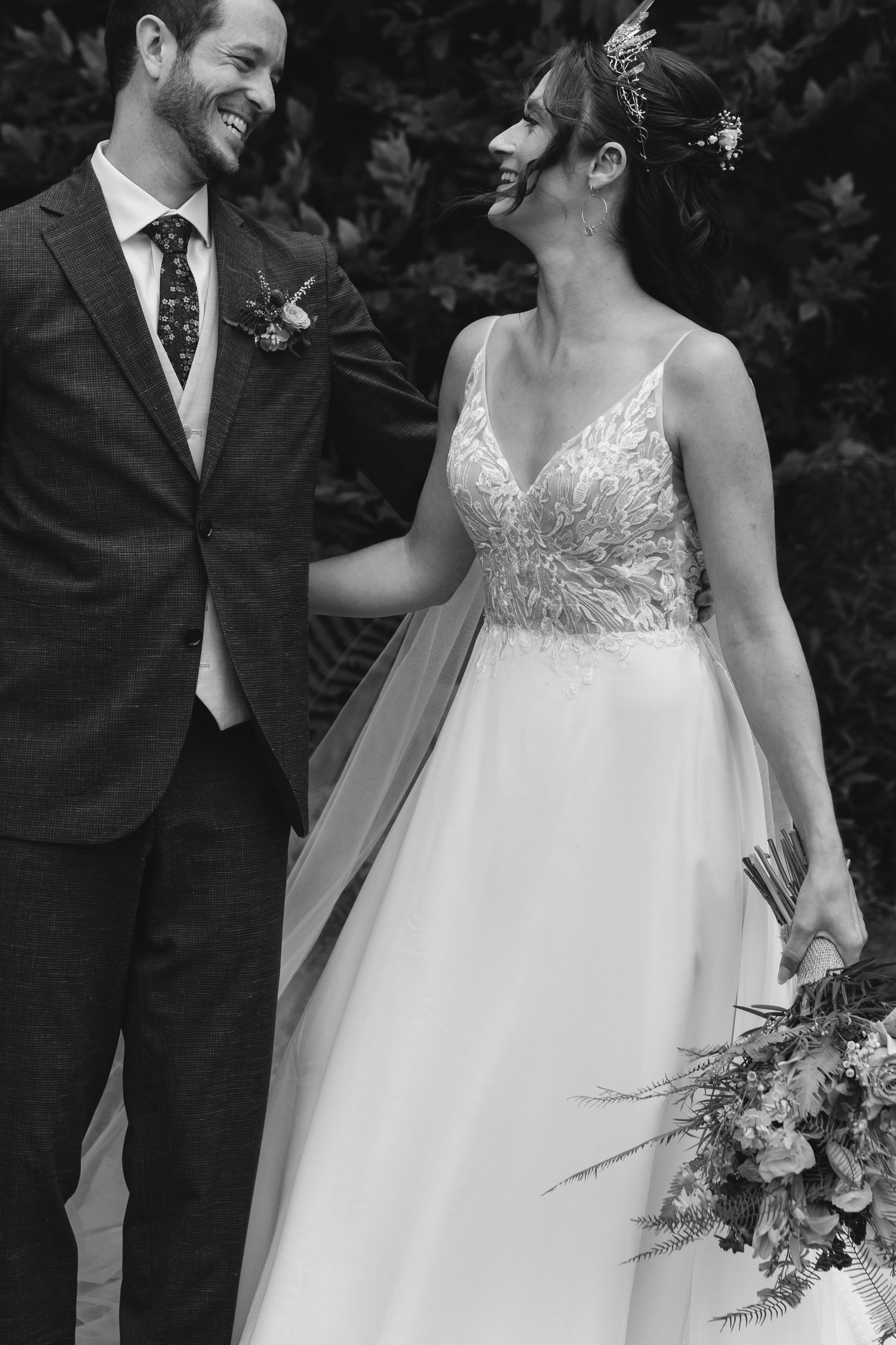 Black and white candid wedding photo showing joyful moment between newlyweds.