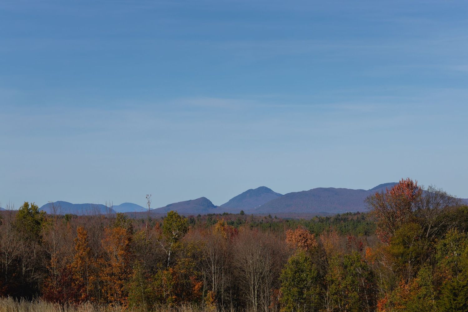 A panoramic autumn landscape shows mountain ranges in the distance with colorful fall foliage in the foreground.