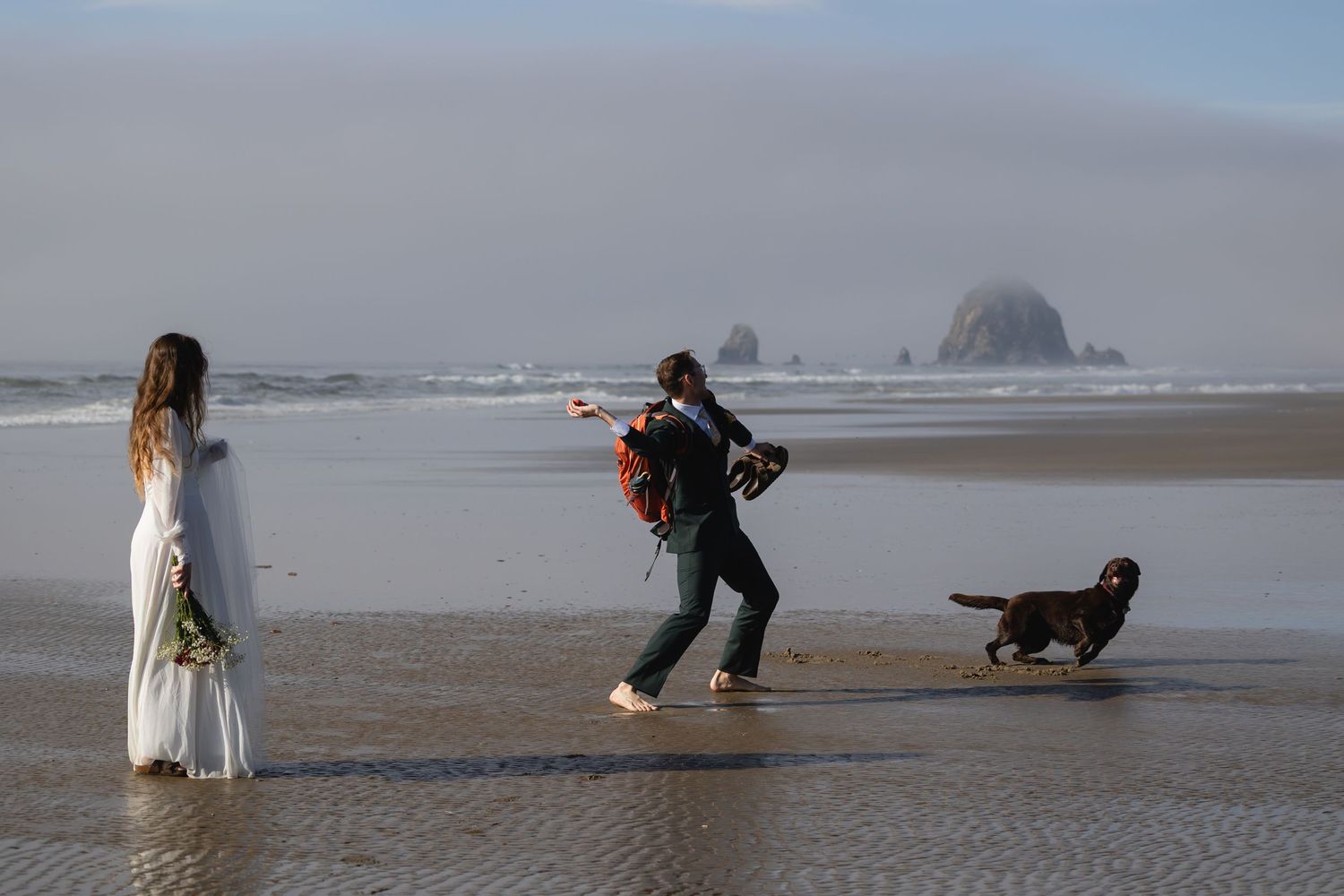 Photographer takes pictures on a misty beach with a dog while capturing a scene near Haystack Rock at Cannon Beach.