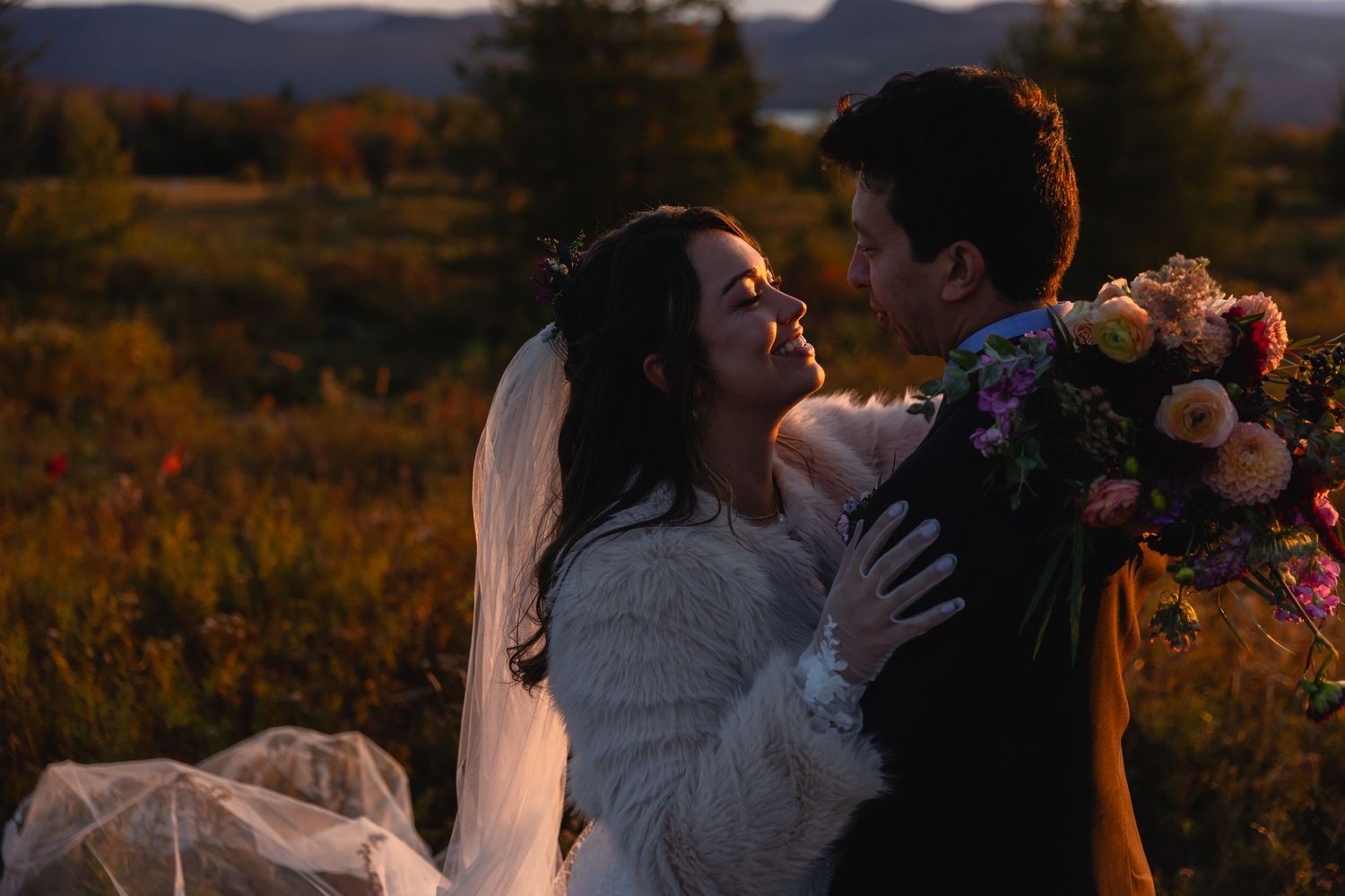 Bride and groom share intimate moment at golden hour with colorful wildflower bouquet in mountains.