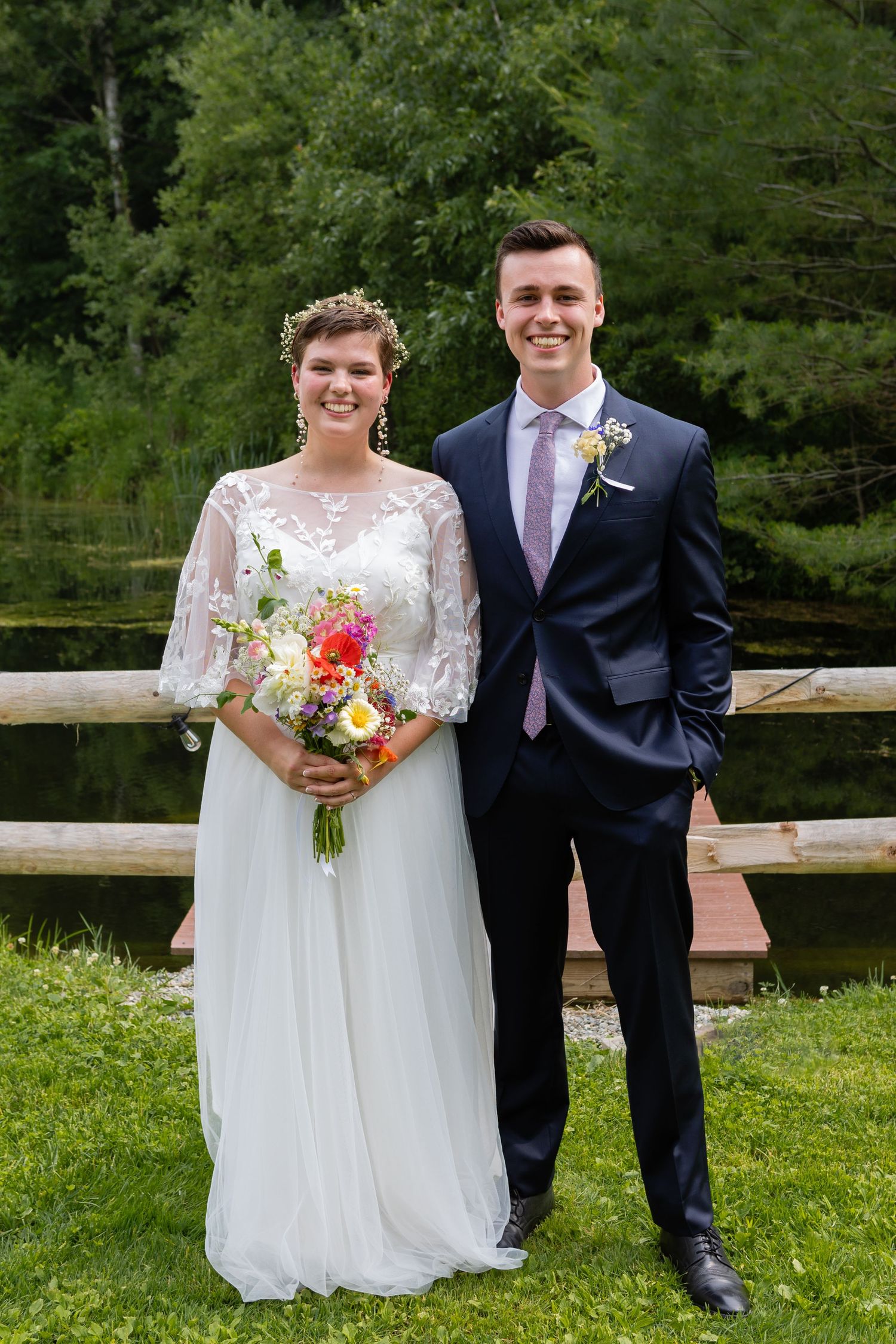 Wedding portrait by wooden fence with colorful summer bouquet.