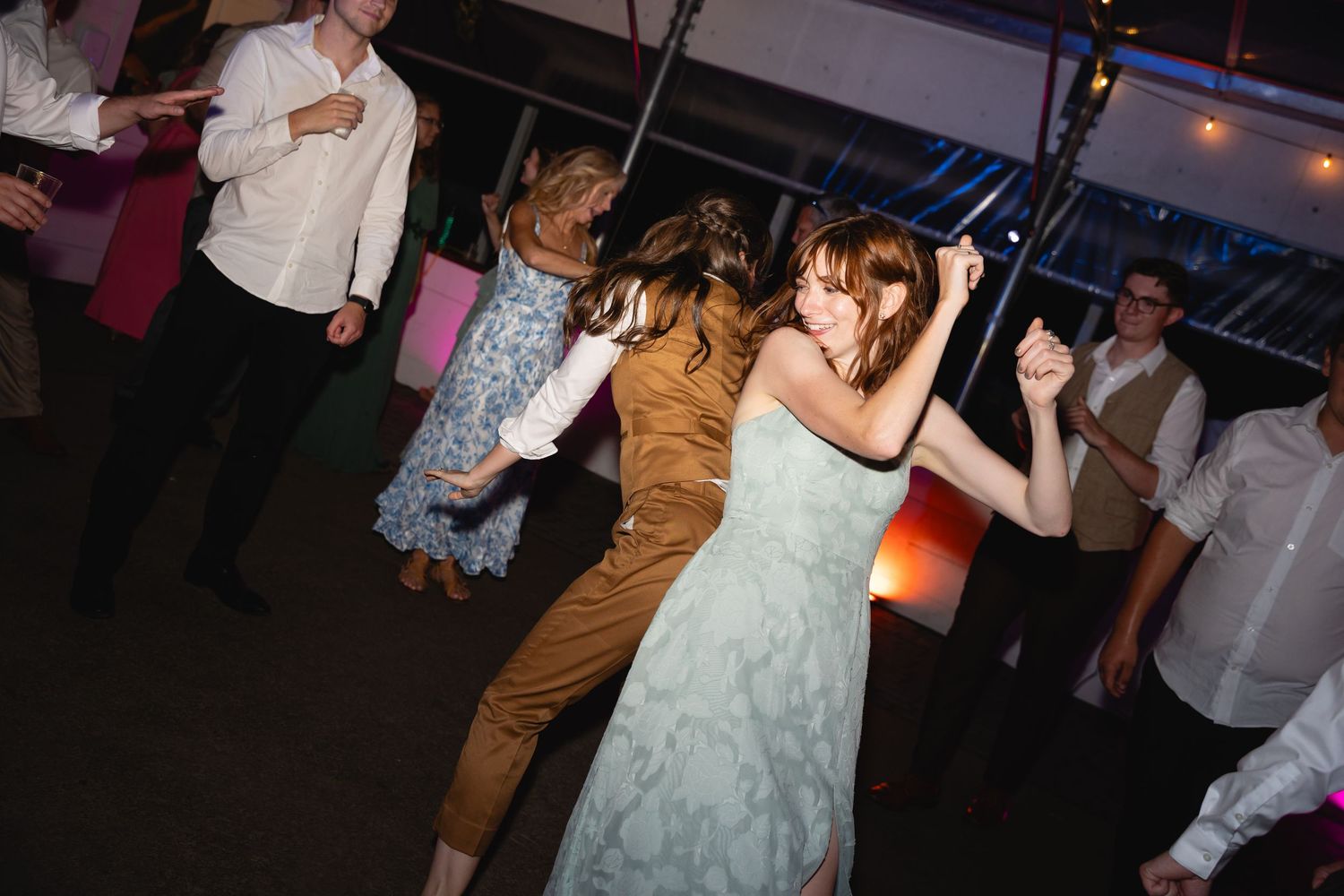 Couples dancing together at a wedding reception under atmospheric lighting and decorations.