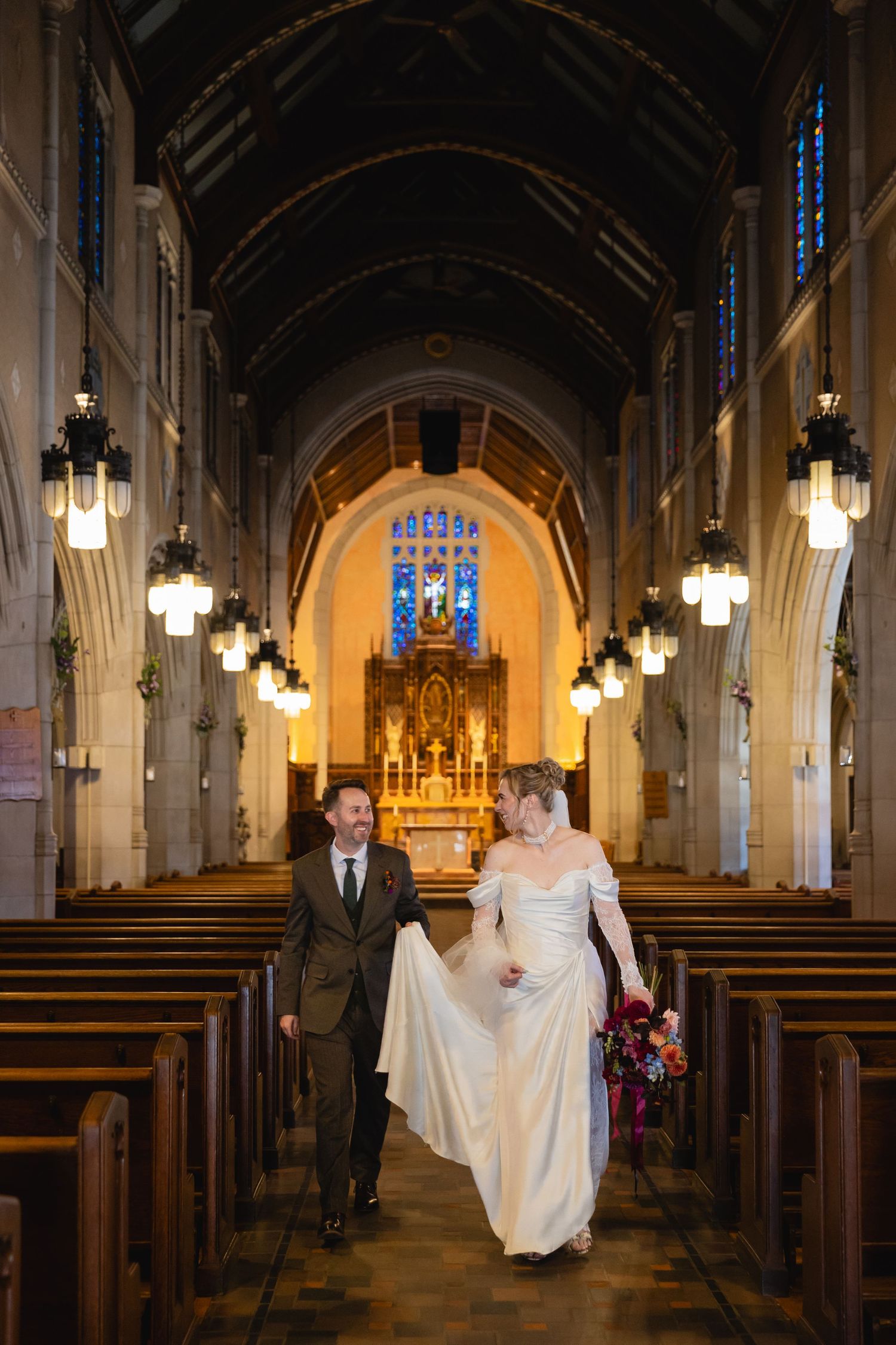 Romantic couple portraits in a gothic church interior with glowing pendant lights and vaulted arches.