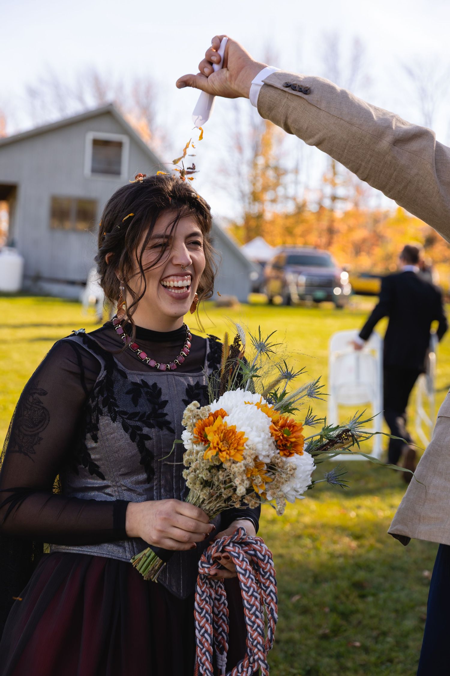 A joyful celebration with flowers and laughter in a sunny outdoor setting with fall colors in the background.