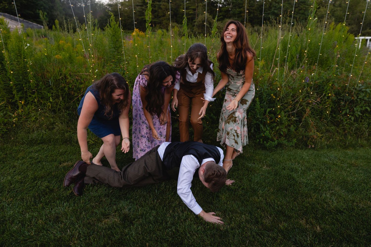 A sequence of photos showing people tumbling onto grass in a domino-like effect outdoors.