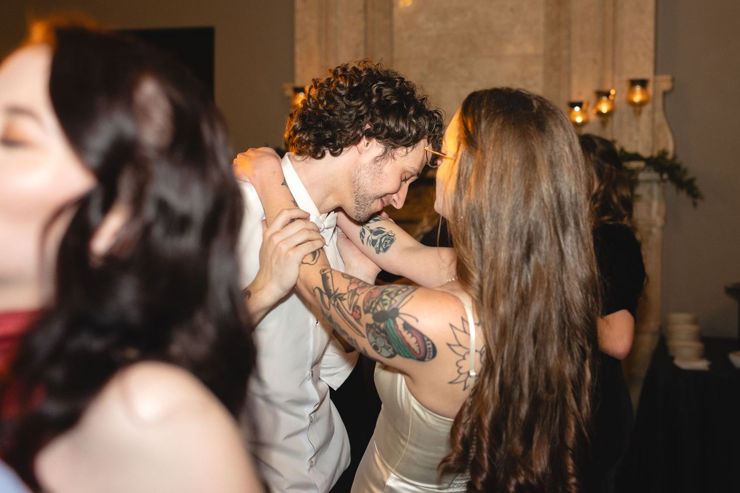 A couple embraces and dances energetically on a dance floor while celebrating at a festive party.