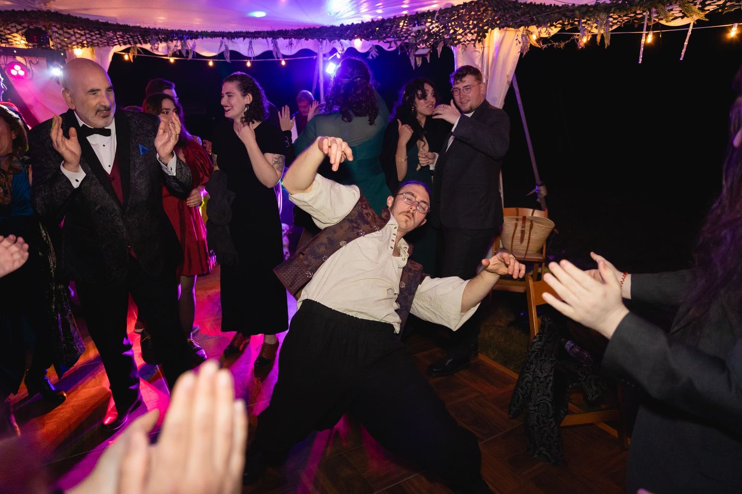Wedding guest energetically dancing and posing on the dance floor at a lively reception.