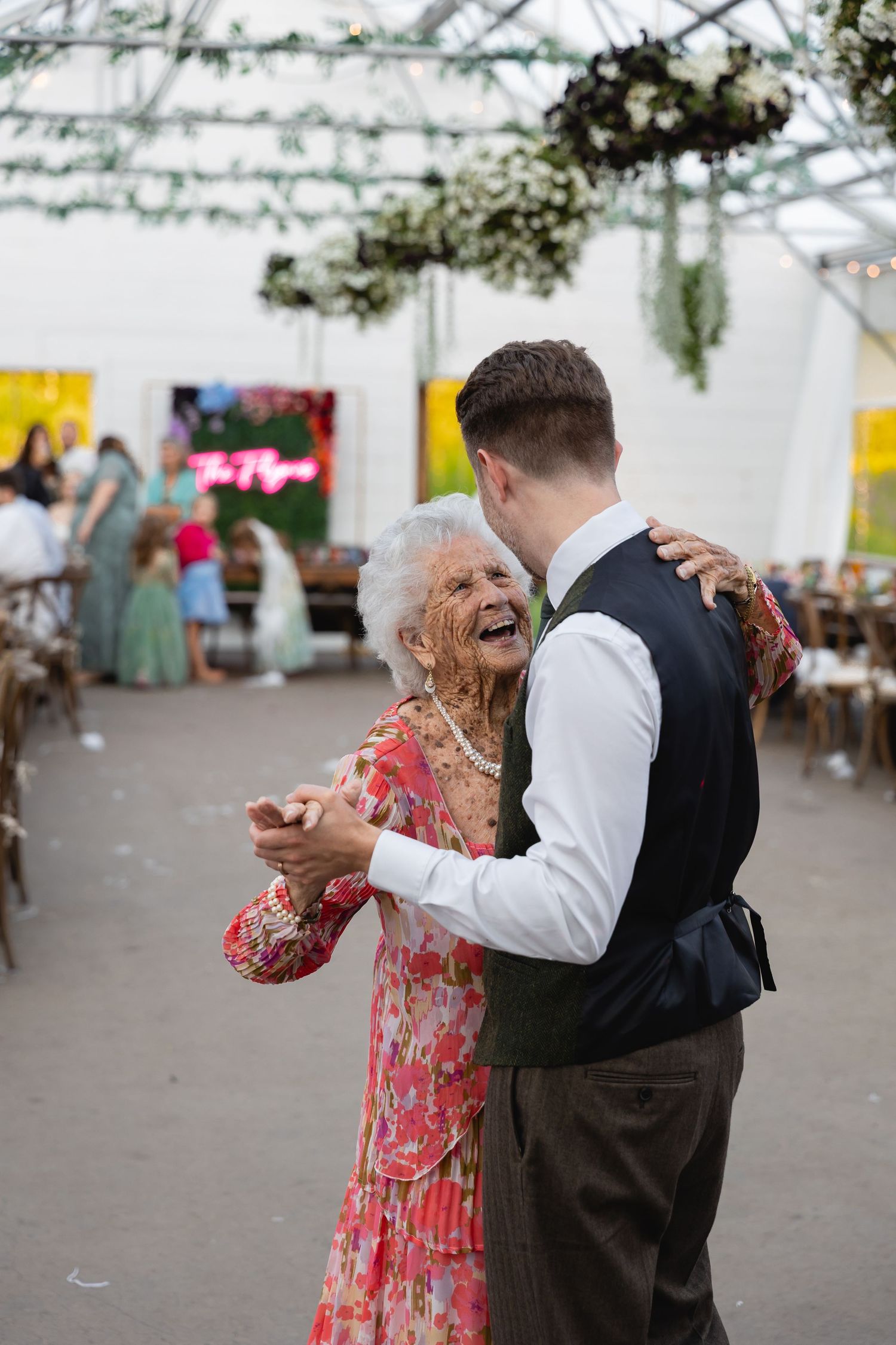 A heartwarming moment captured at a wedding reception as dancers share a joyful dance under a white tent.