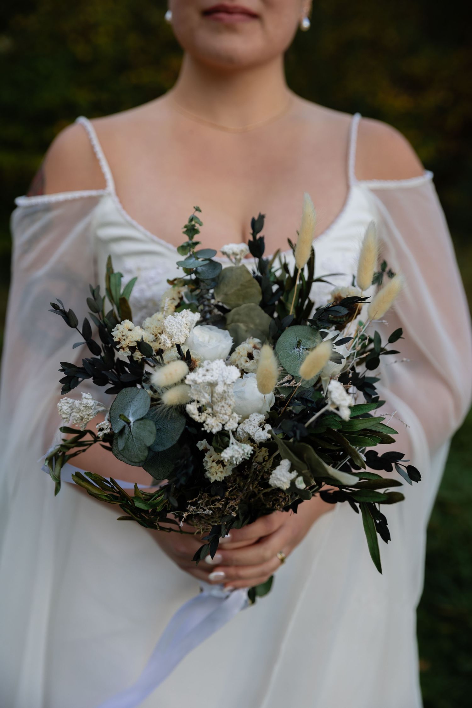 Close-up of an elegant white and green wedding bouquet with eucalyptus and fresh flowers.