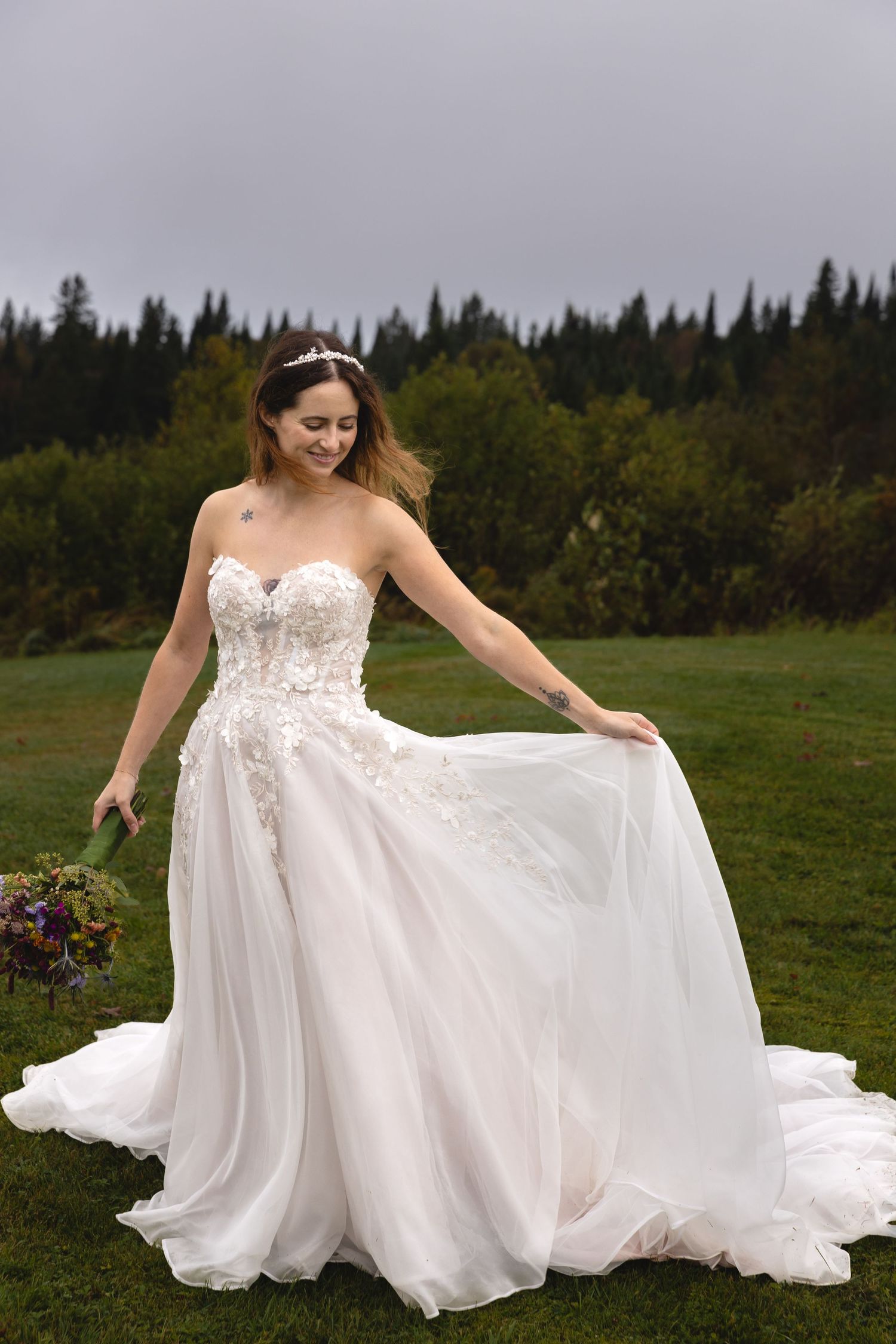 A flowing white wedding gown with lace details twirls gracefully in a mountain meadow.