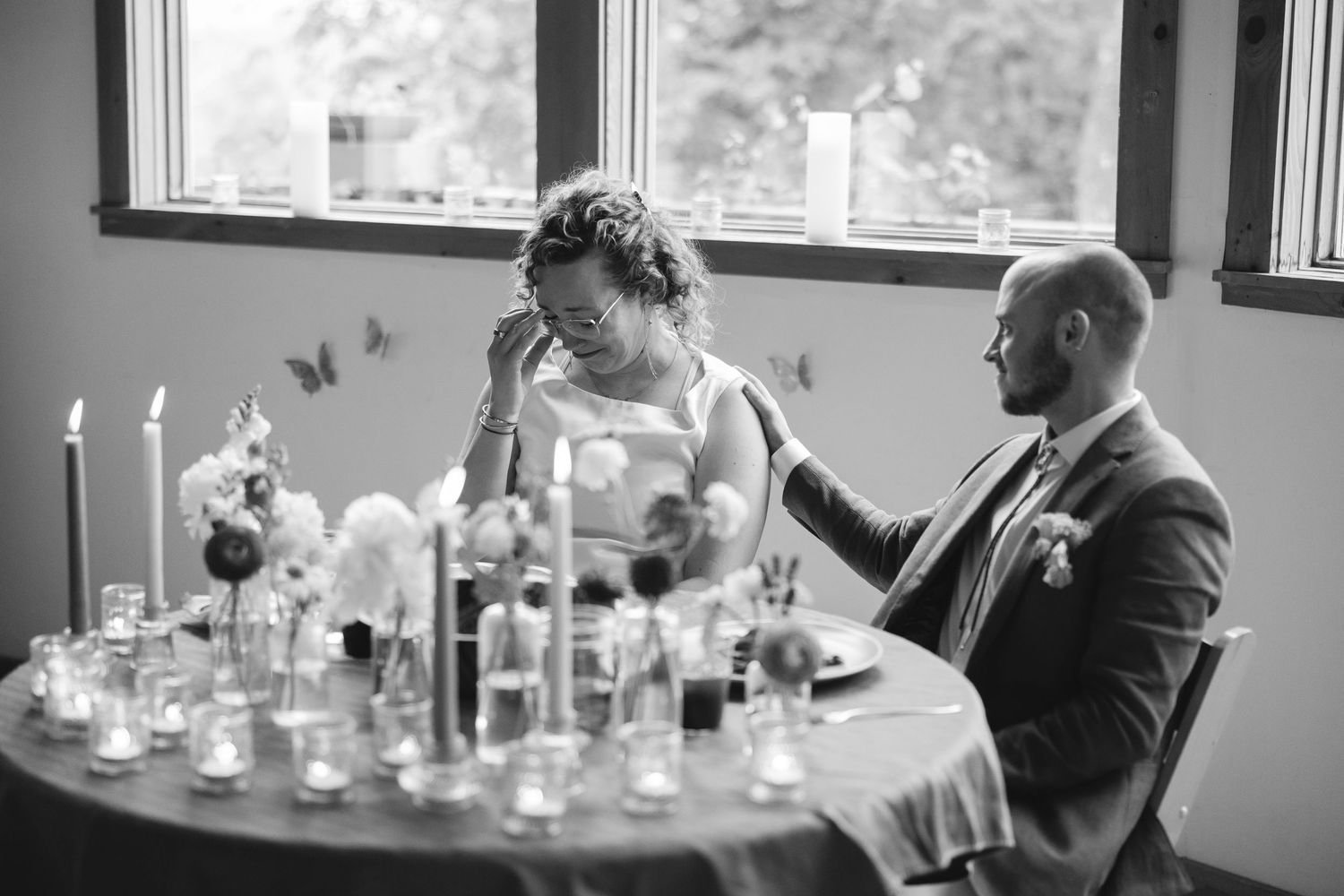 Wedding guests sit at round tables decorated with elegant candle centerpieces in a modern reception venue.