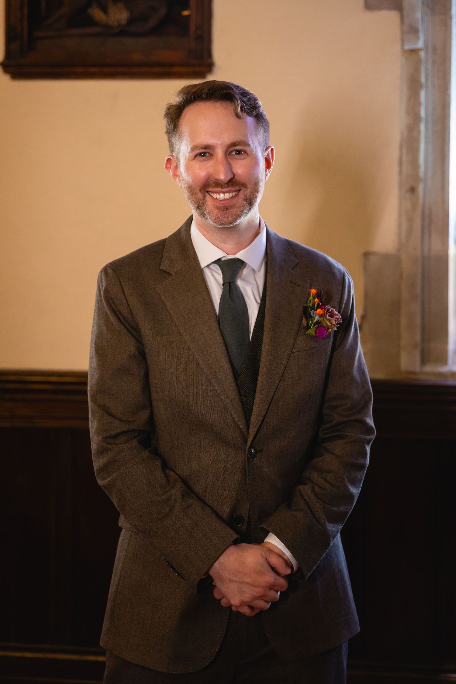 A groom in a brown tweed suit smiles warmly in a series of four similar portrait shots.