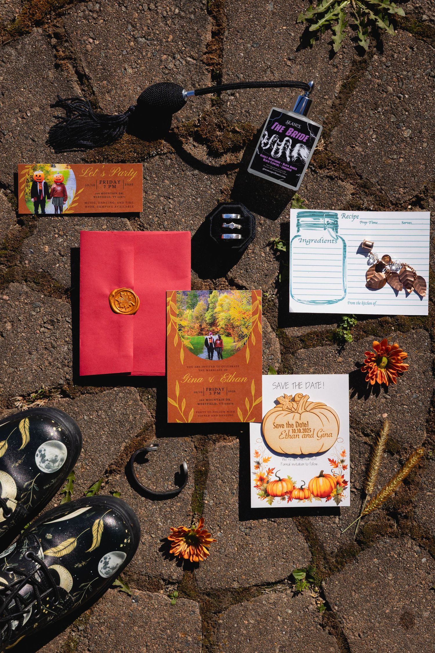 Wedding invitation cards and decorative elements laid out on a stone or brick surface with autumn flowers and decor.