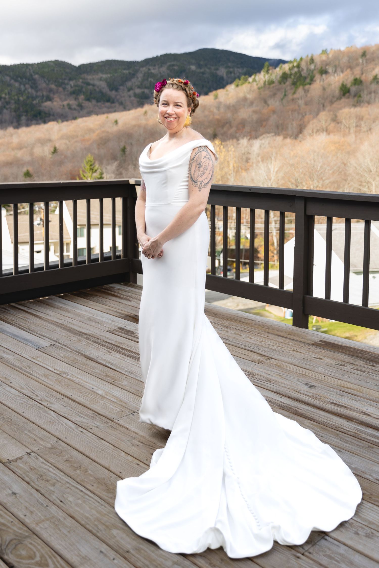 Wedding dress with flowing train photographed on wooden deck with mountain backdrop.