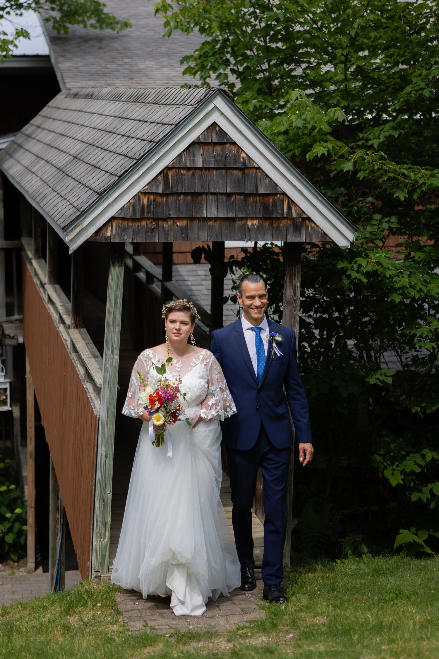 A couple exits a rustic wooden gazebo during their wedding ceremony.
