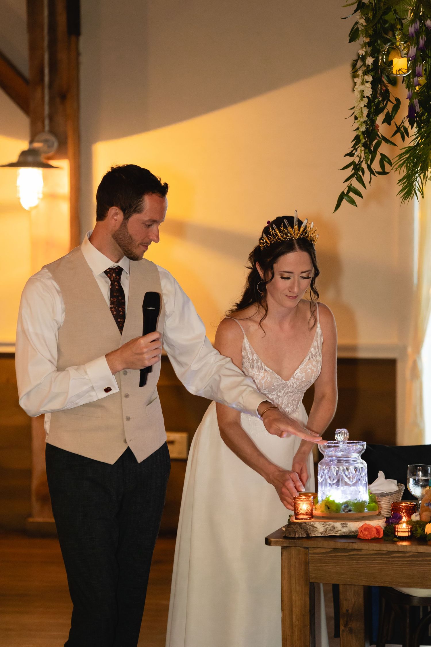 Wedding reception moment with couple speaking at rustic wooden table.