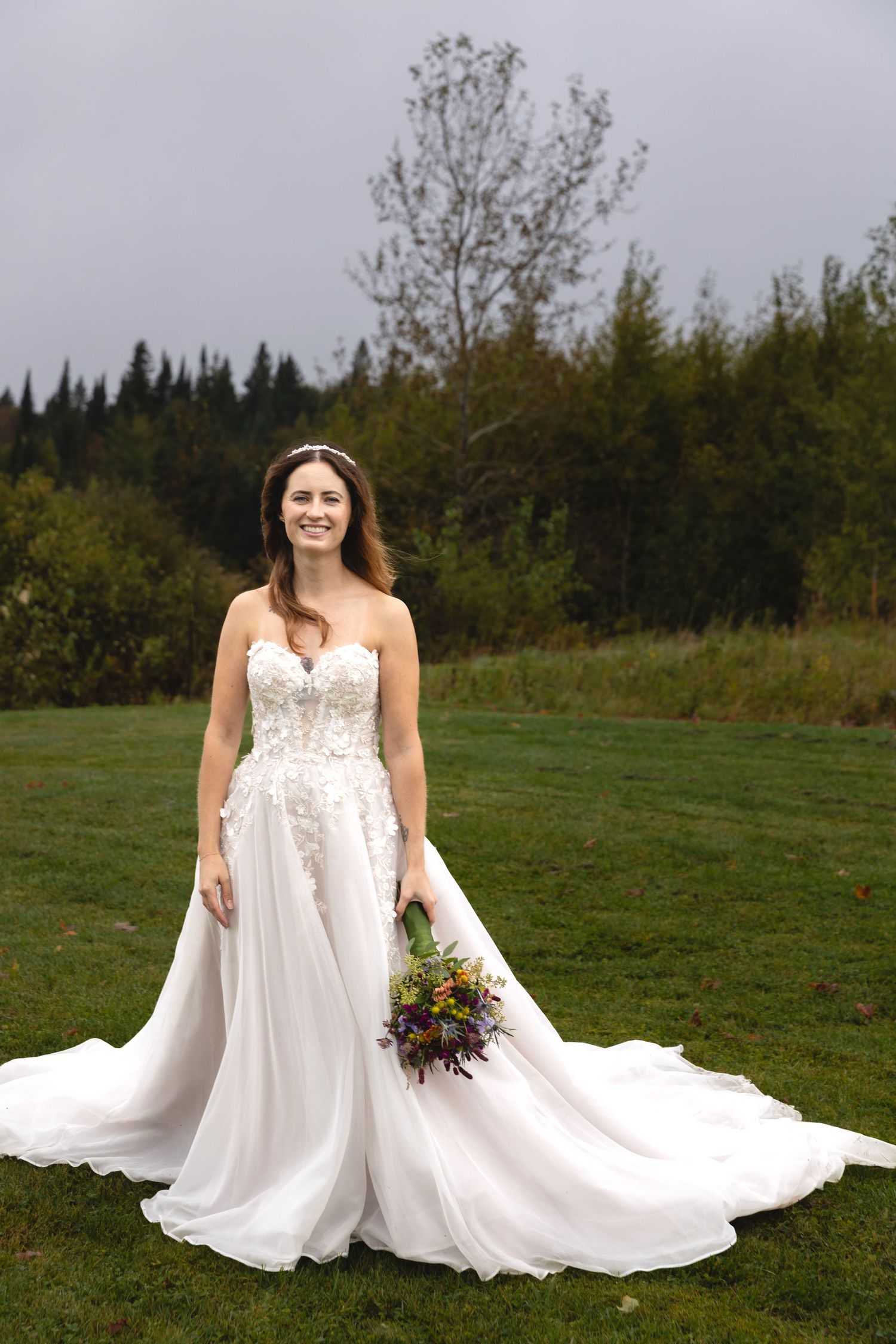 A stunning wedding dress with lace details flows elegantly against a mountain landscape.