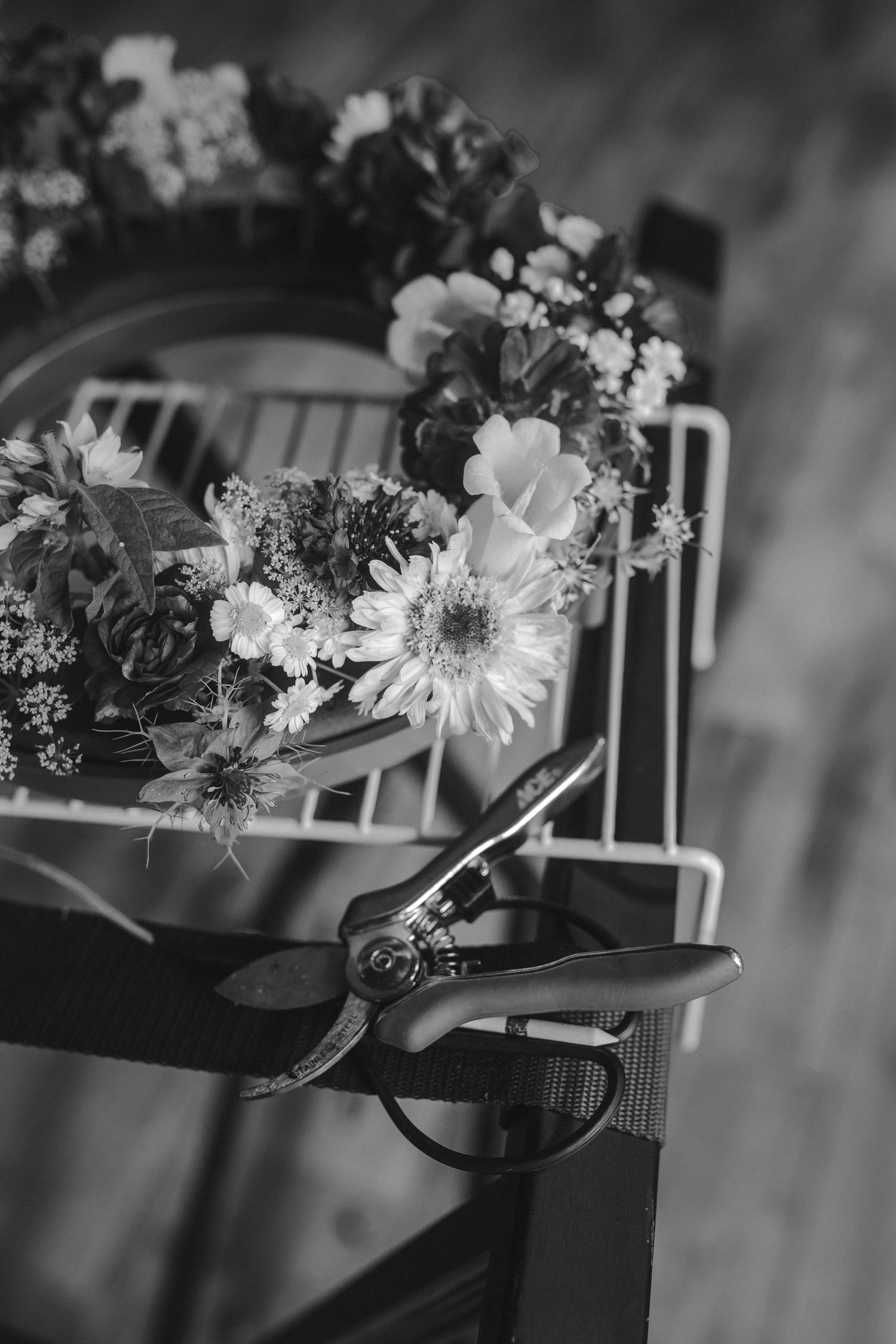 Black and white image of fresh flower bouquet with garden shears on wooden surface.