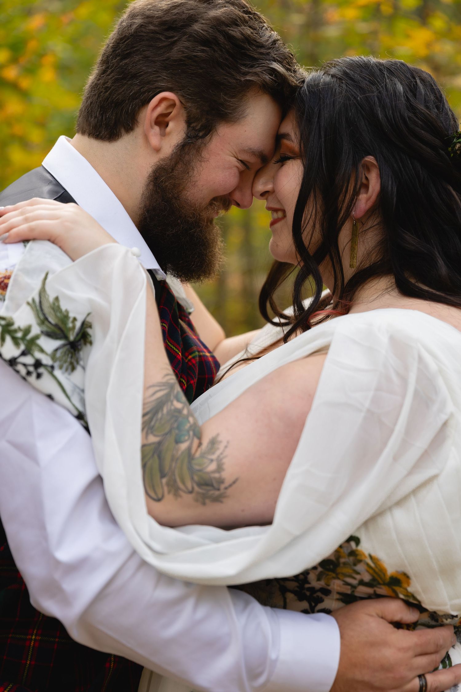 Intimate moment between newlyweds surrounded by golden fall foliage.
