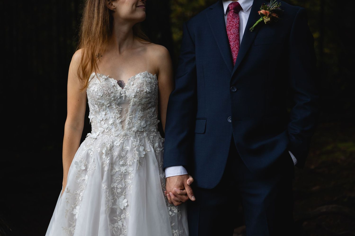 An elegant close-up photo focusing on intricate lace details of a strapless wedding gown.