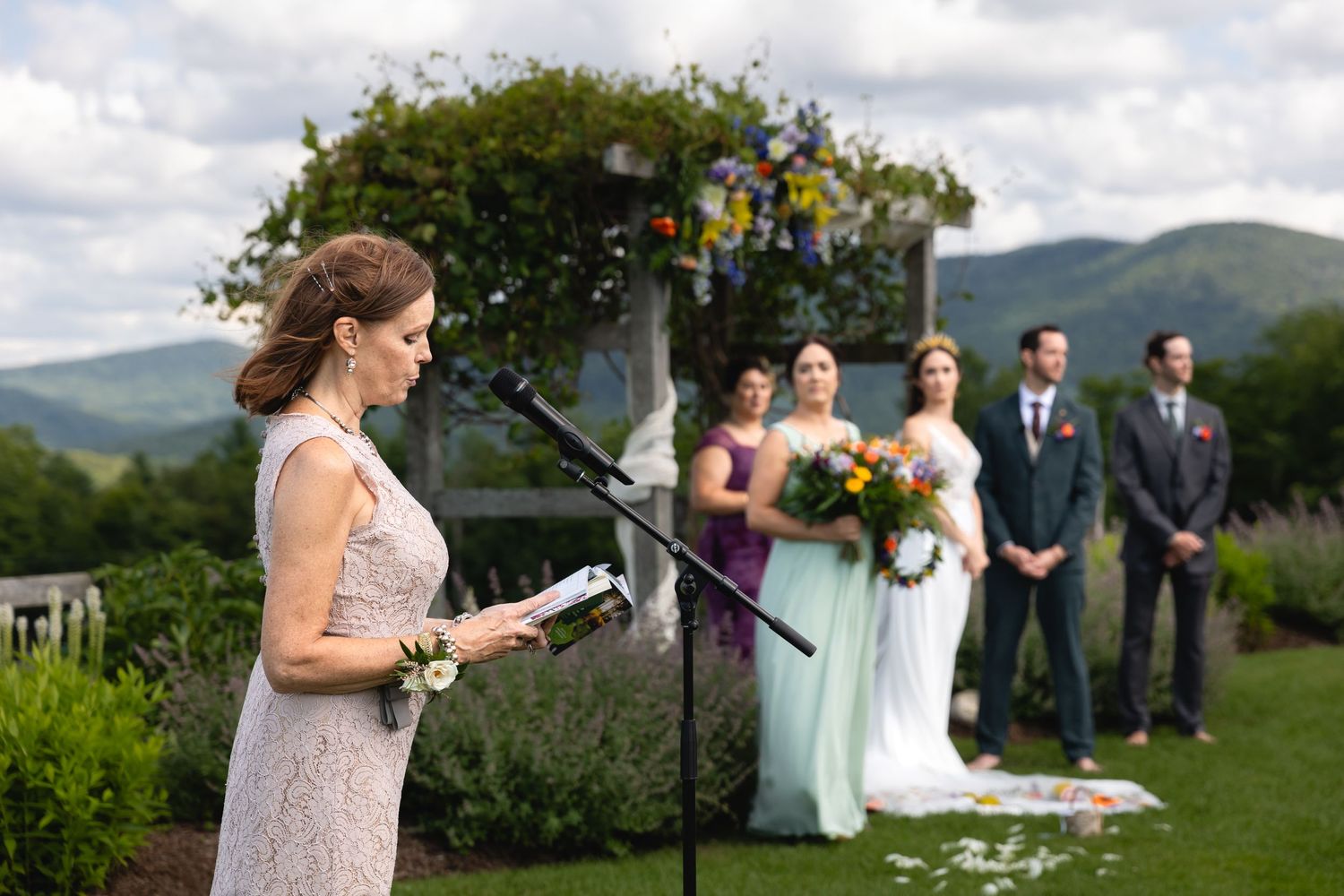 A speaker addresses wedding guests during an outdoor mountain ceremony.
