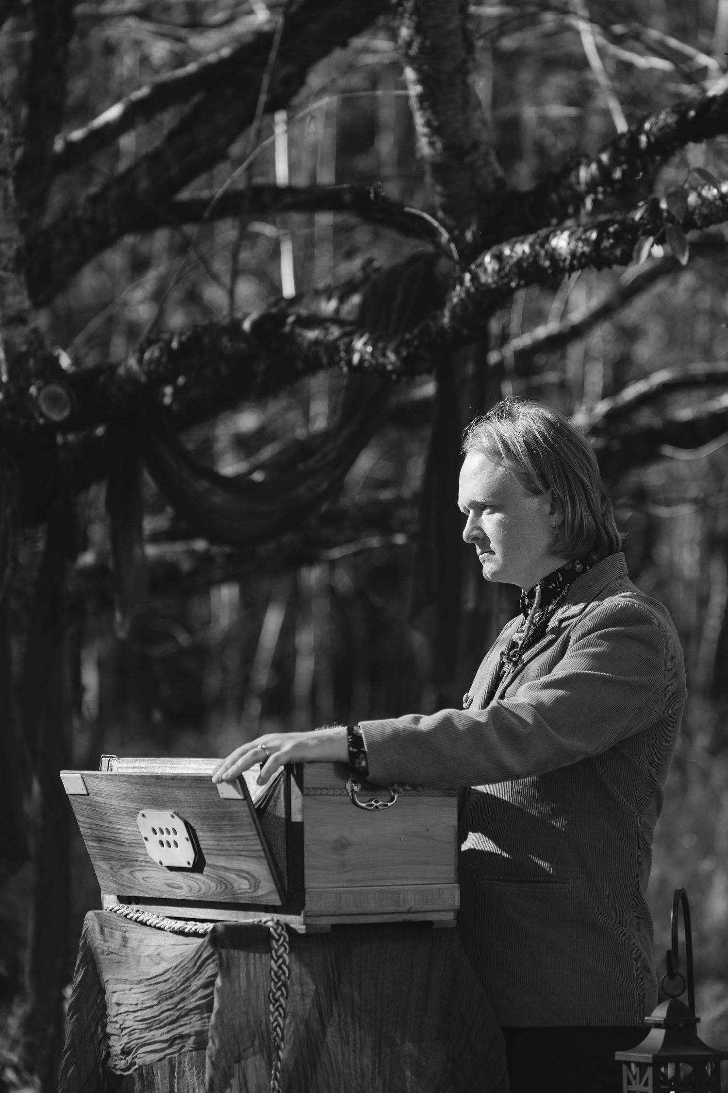 A black and white sequence showing a person reading and writing at a desk in a natural outdoor setting.