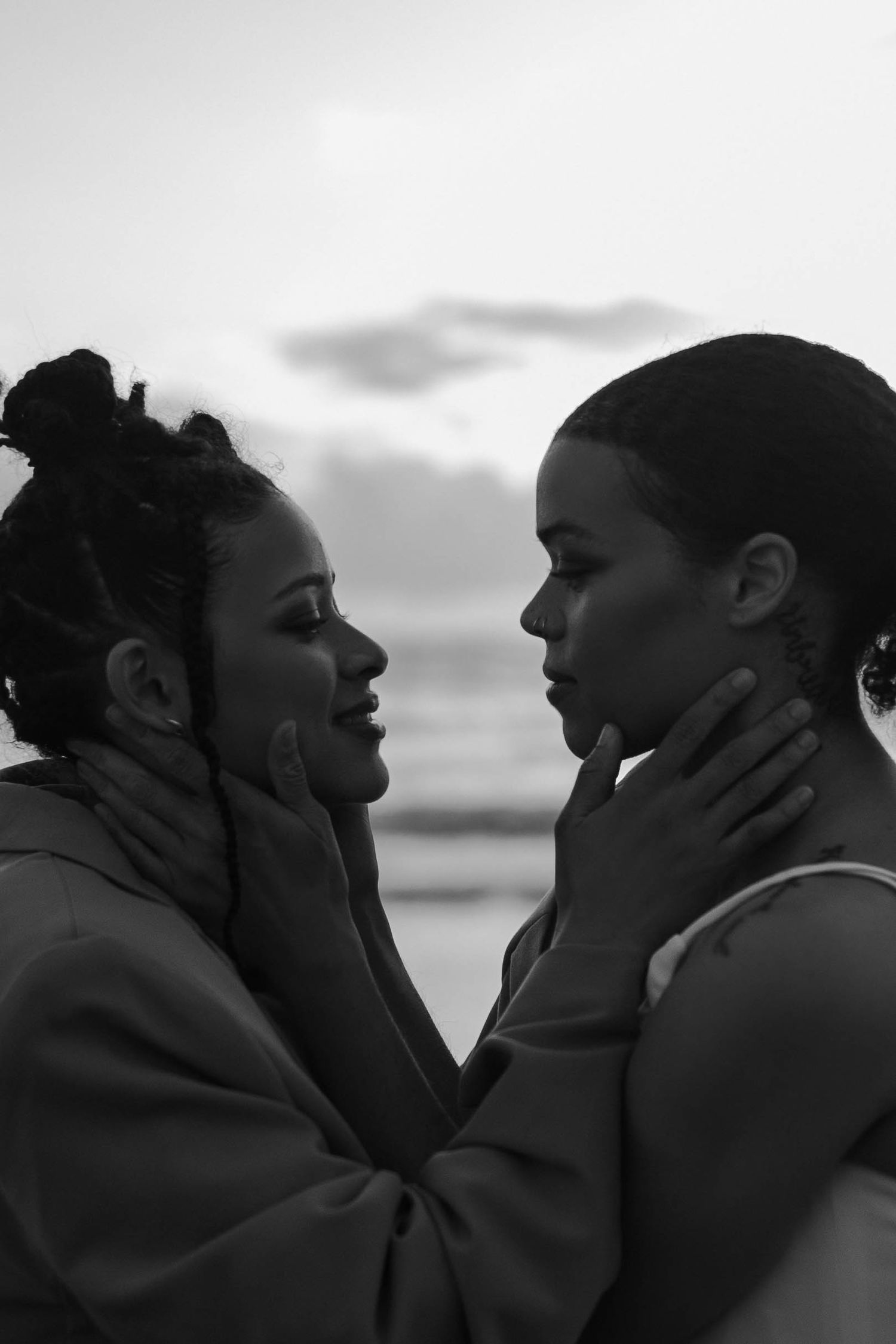 An intimate black and white portrait of a couple sharing a loving moment on the beach.