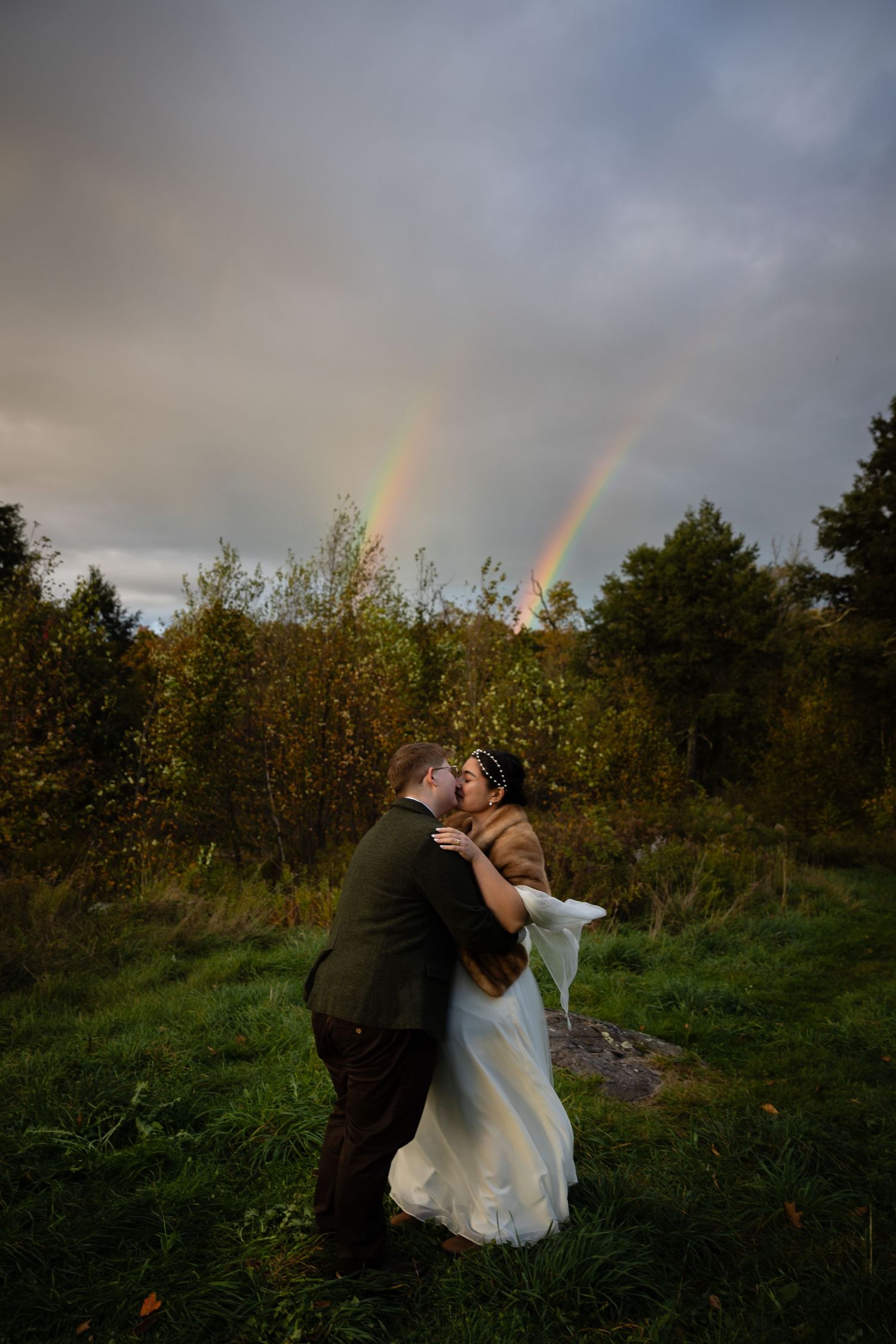 A romantic wedding moment captured with double rainbows illuminating the autumn scenery.