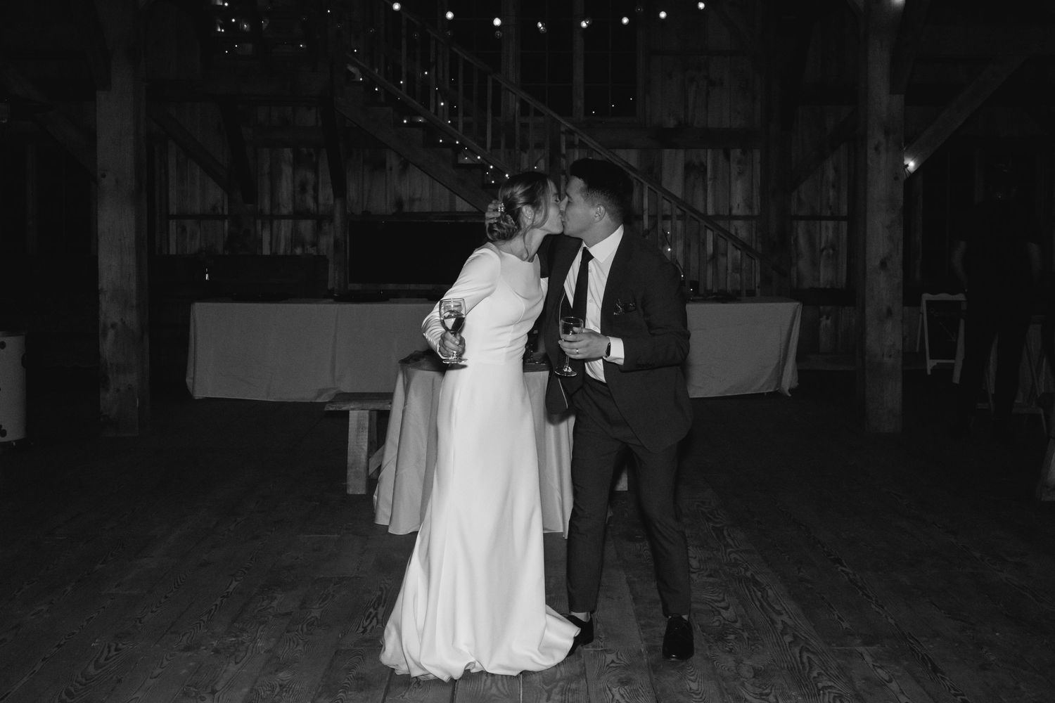 A couple in formal wedding attire sharing a romantic first dance on a dimly lit dance floor.