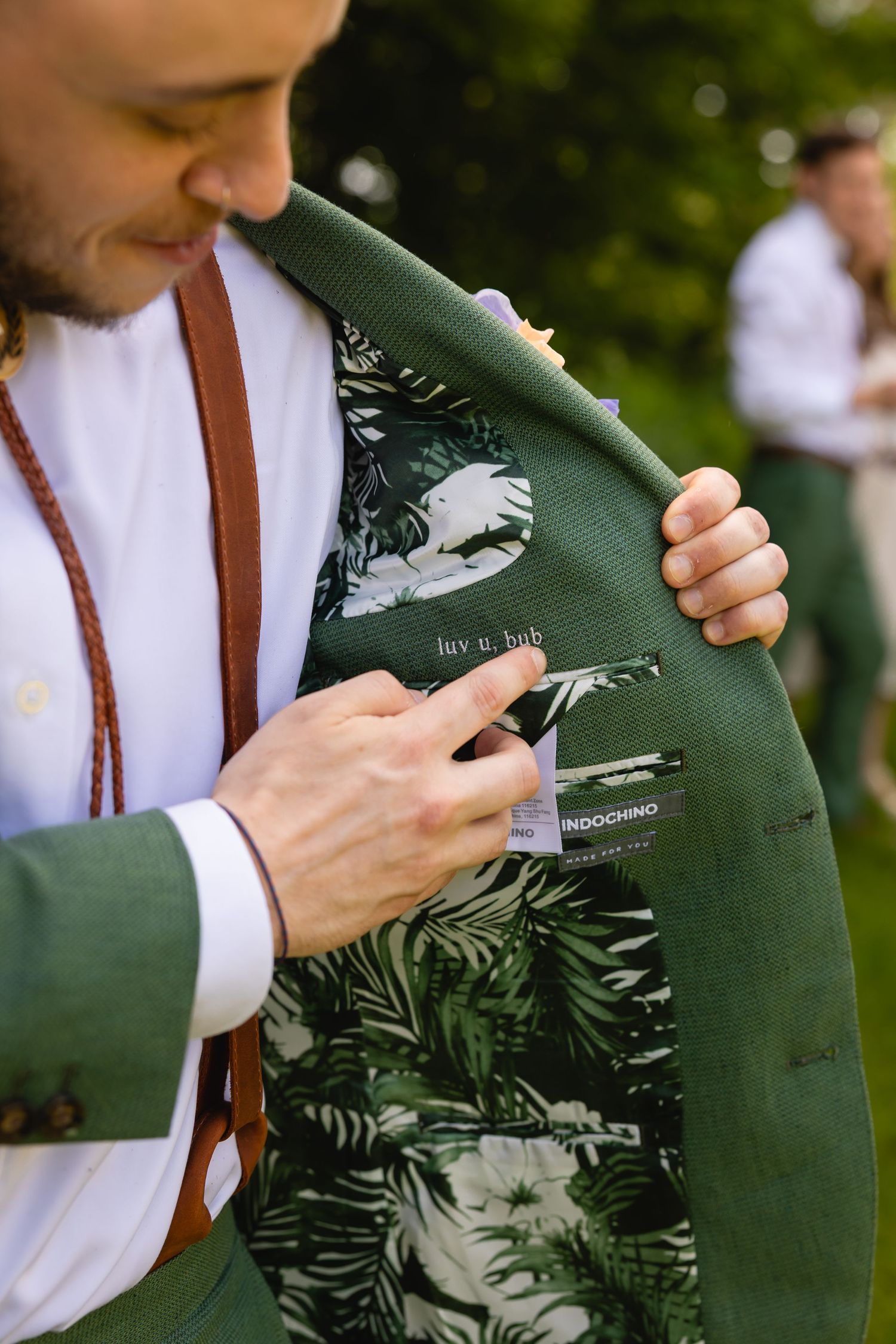 Close-up view of green suit jacket with tropical floral print lining being shown at formal event.