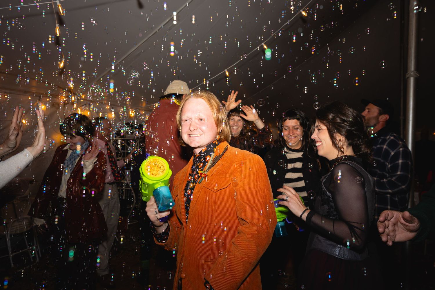 Concert crowd celebrates with confetti falling while people dance and enjoy the festive atmosphere at a live music event.
