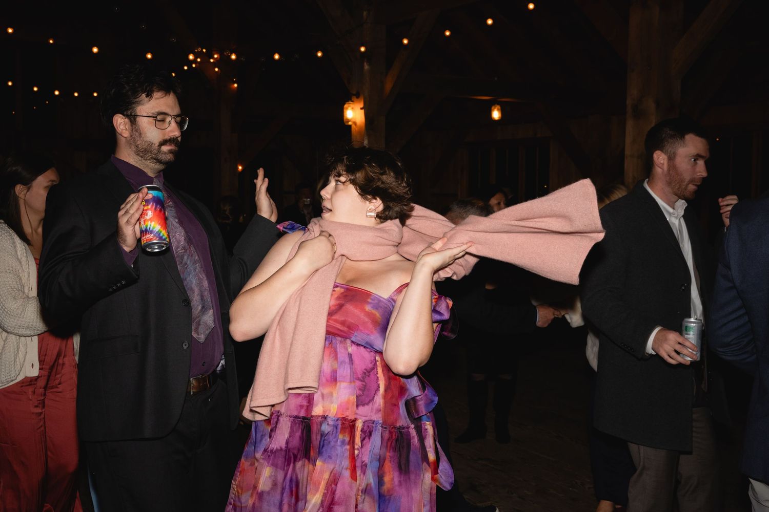 Party guests dance and socialize at a nighttime outdoor event with string lights illuminating the festive atmosphere.