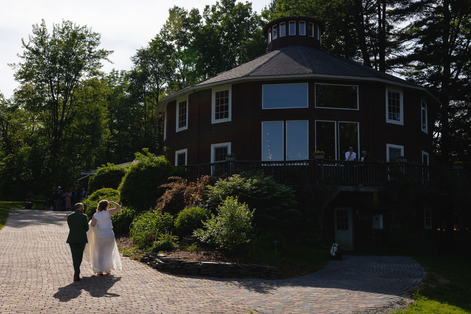 Modern dark-colored house exterior with grey shingle siding and multiple windows on a sunny day.