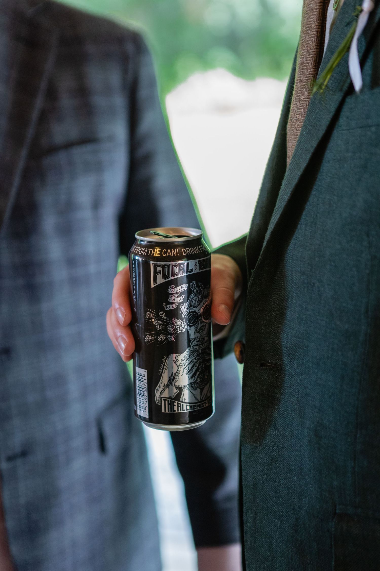 Two people holding a craft beer can at a formal event.