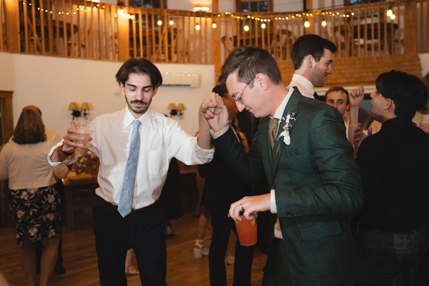 Guests celebrating and dancing energetically at an indoor wedding reception venue.