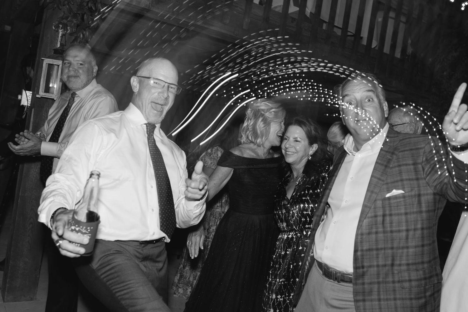 People enjoying themselves while dancing under string lights at an evening celebration.