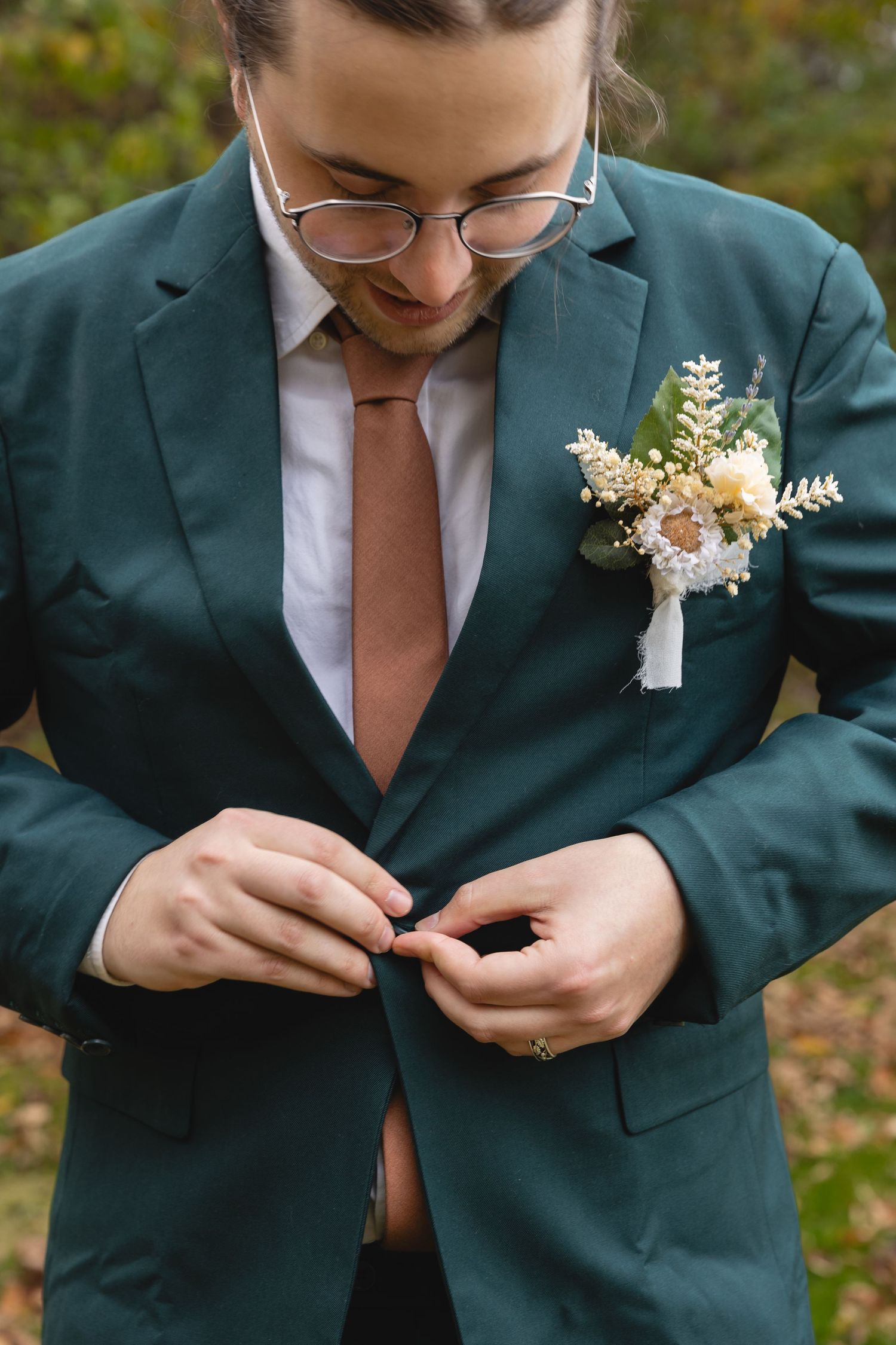 Close-up of emerald green suit jacket with boutonniere and copper tie.