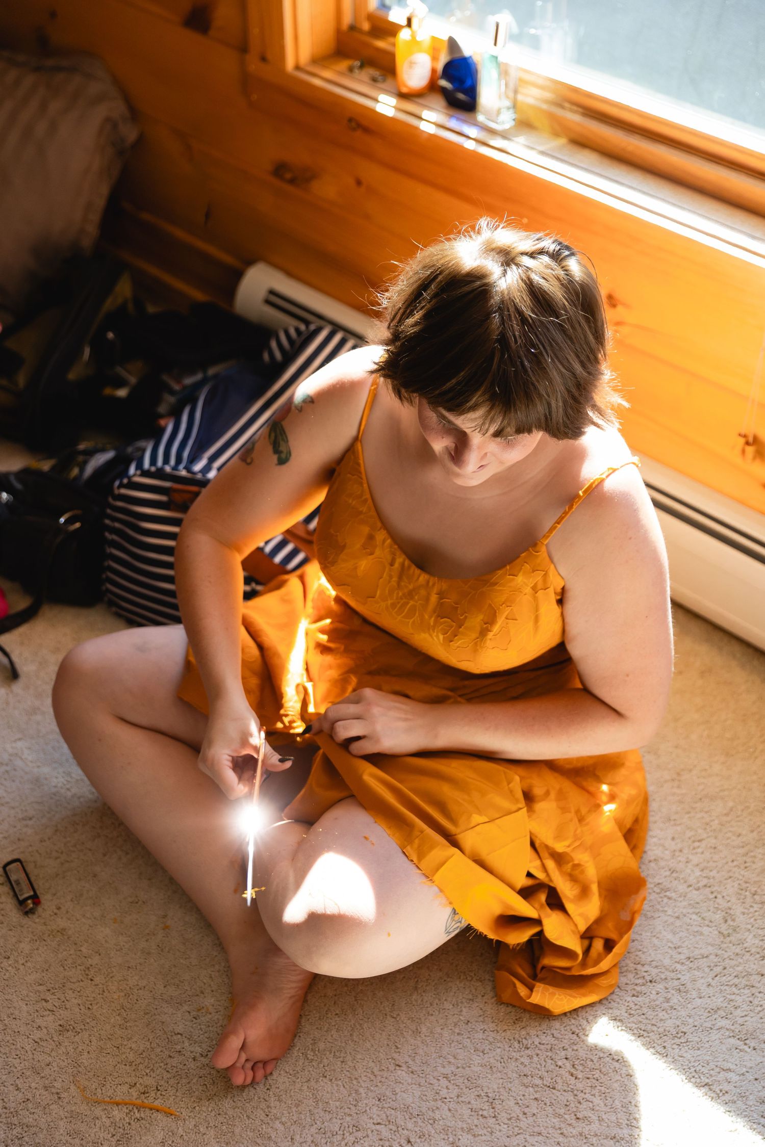 A child sits on a carpeted floor in warm sunlight streaming through a window while drawing or writing.