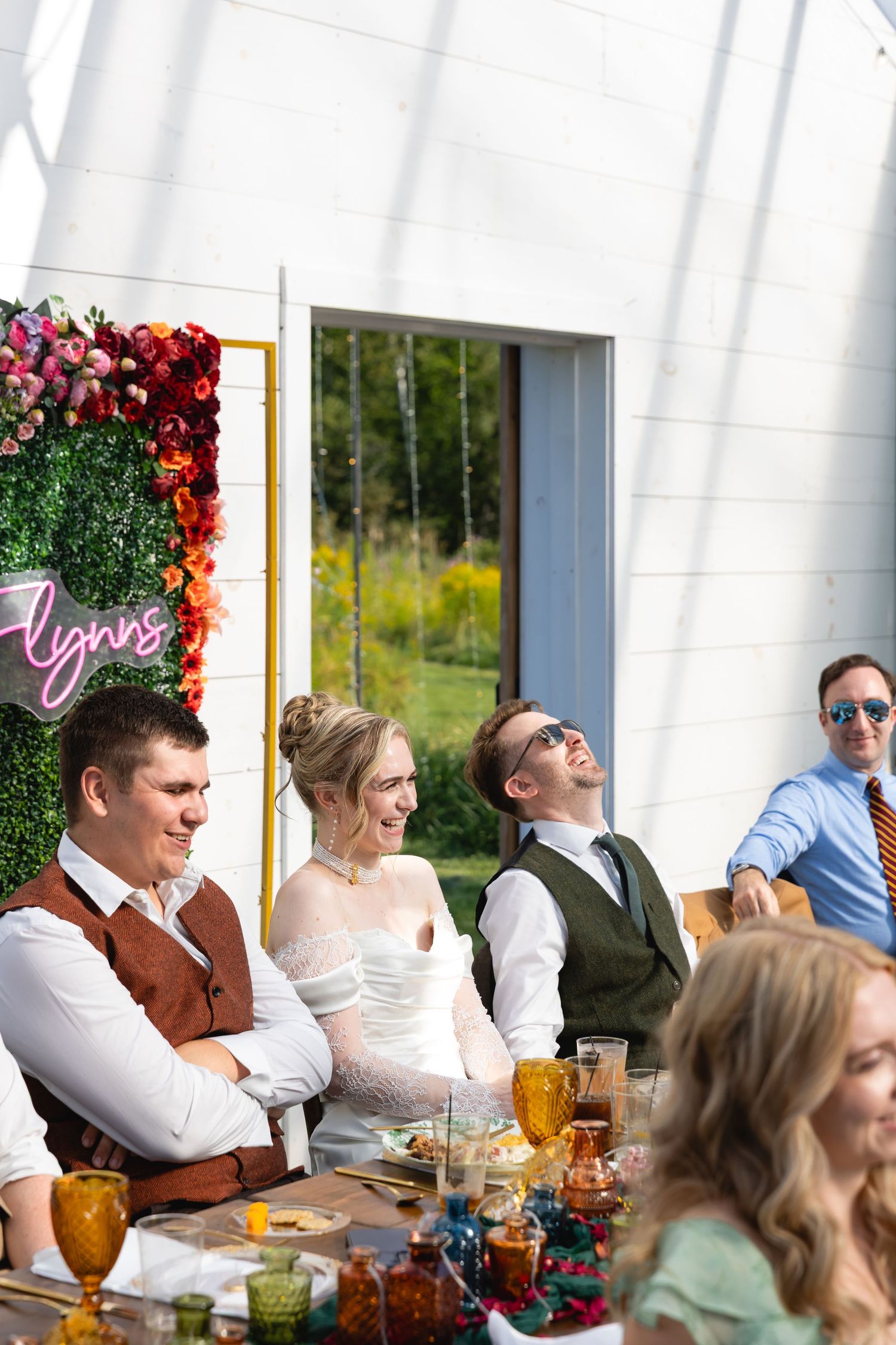 Wedding reception guests seated at long tables with amber glassware and floral decorations in an elegant venue.