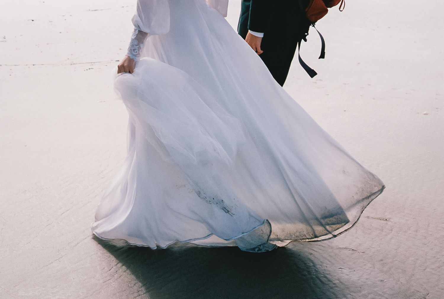 A bride in a flowing white gown walks along a snowy winter landscape creating ethereal movement in her dress.