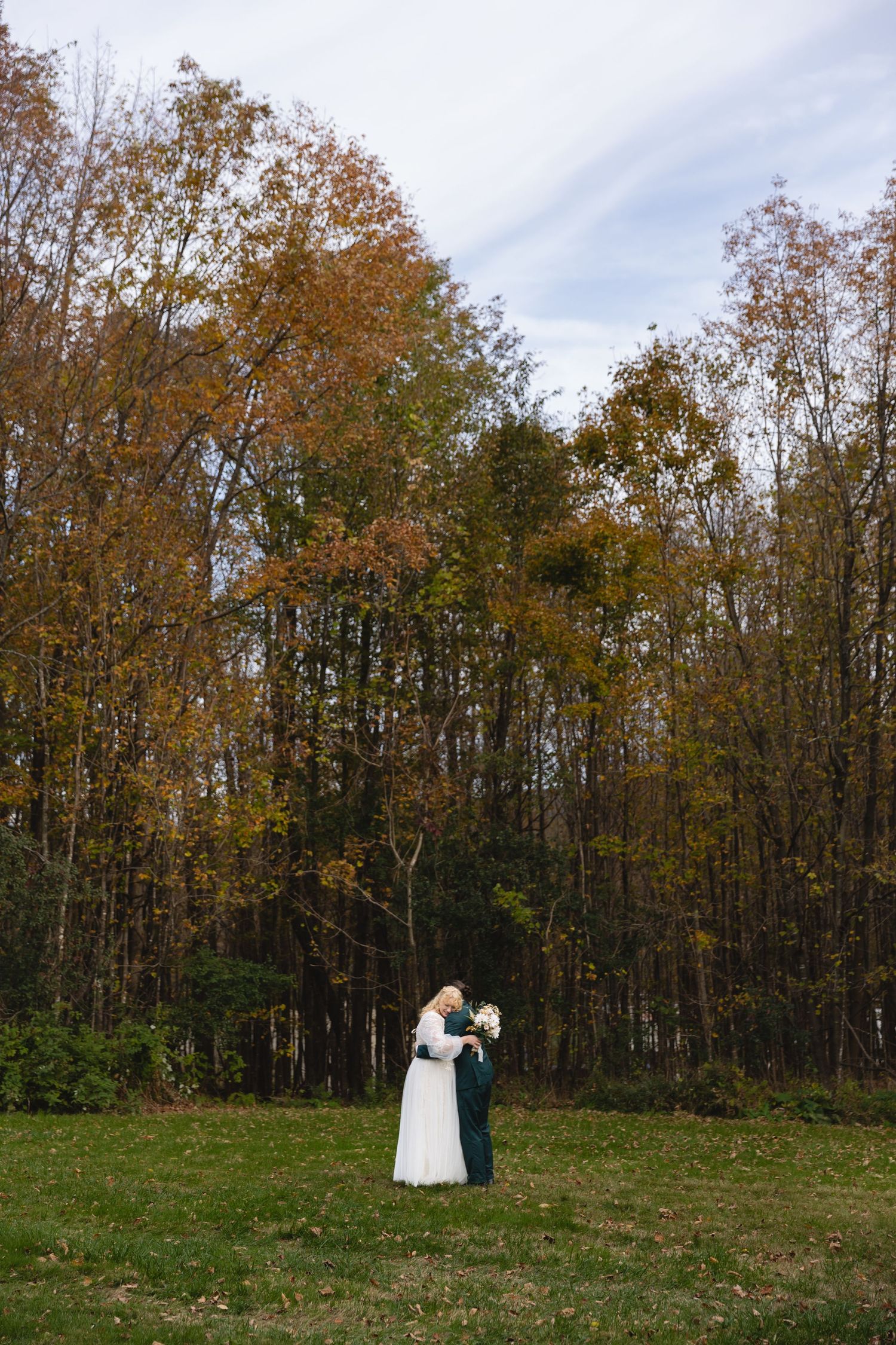 Couple dancing in an autumn field surrounded by colorful fall foliage.