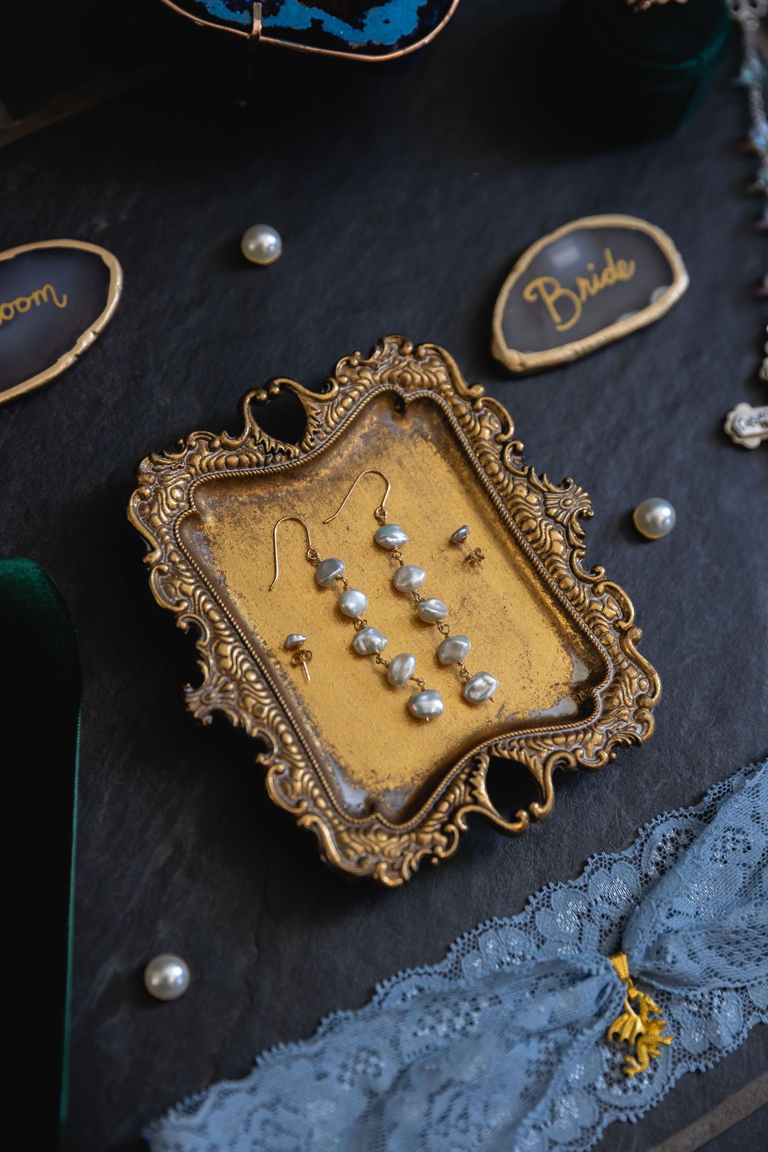 Vintage gold brooch with pearls displayed on dark fabric with delicate blue lace trim.